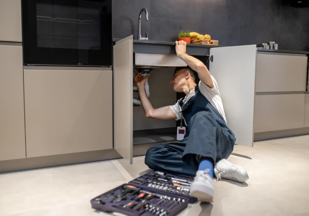 household-repair-middle-aged-man-inspecting-pipe-touching-hand-sink-stylish-modern-kitchen
